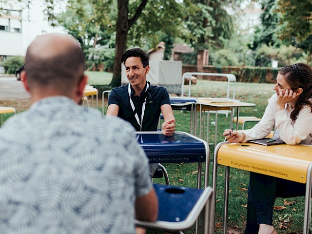 Studenten und Studentinnen lernen zusammen draußen im grünen.