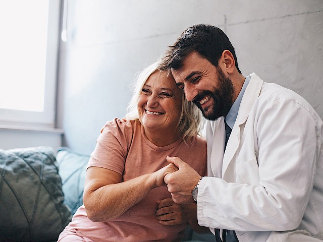 Doctor is happy together with his patient and hugs her.