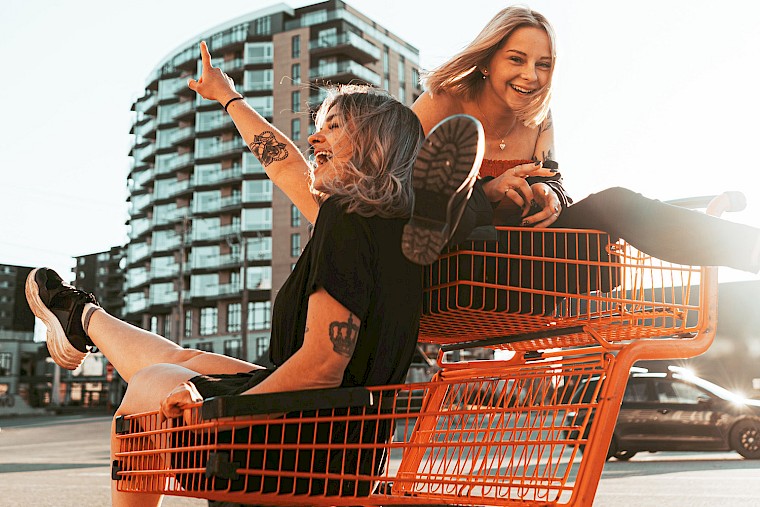 Girlfriends drive around in shopping carts.