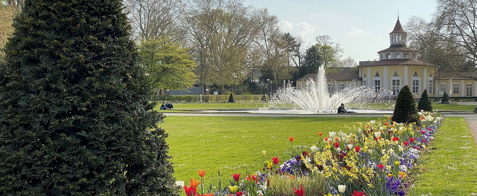 Parkanlage mit blühenden und Springbrunnen.